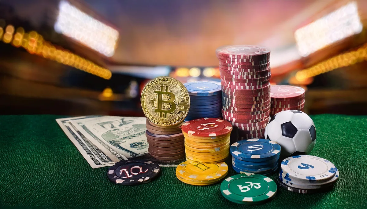 Stacks of casino chips with coins and a football on green felt