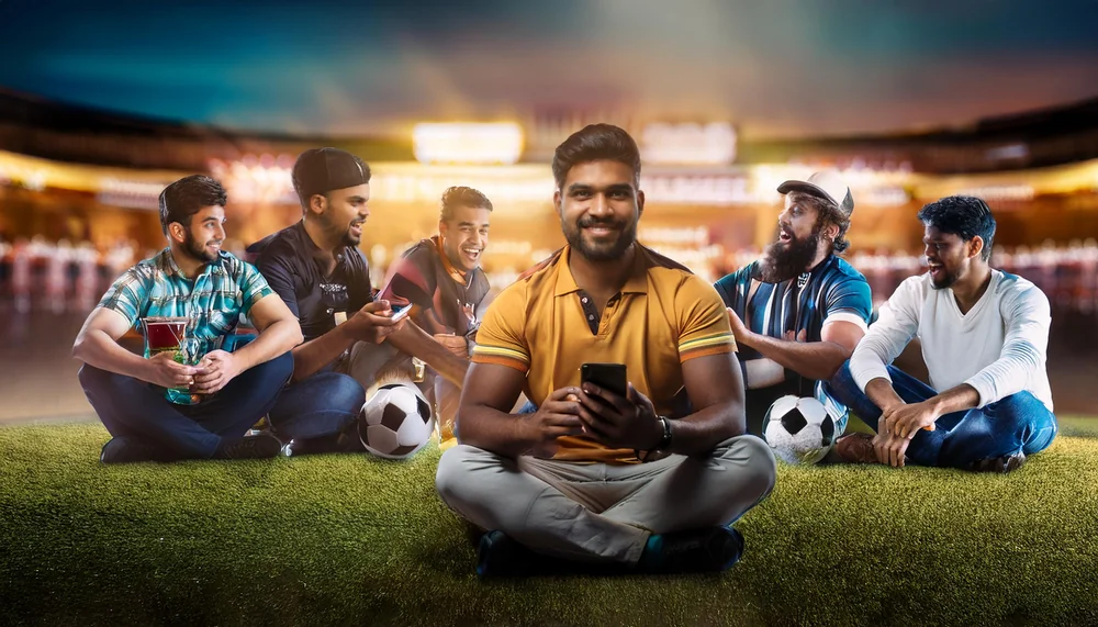 Group of Indian cricket fans checking live scores on a phone at a stadium