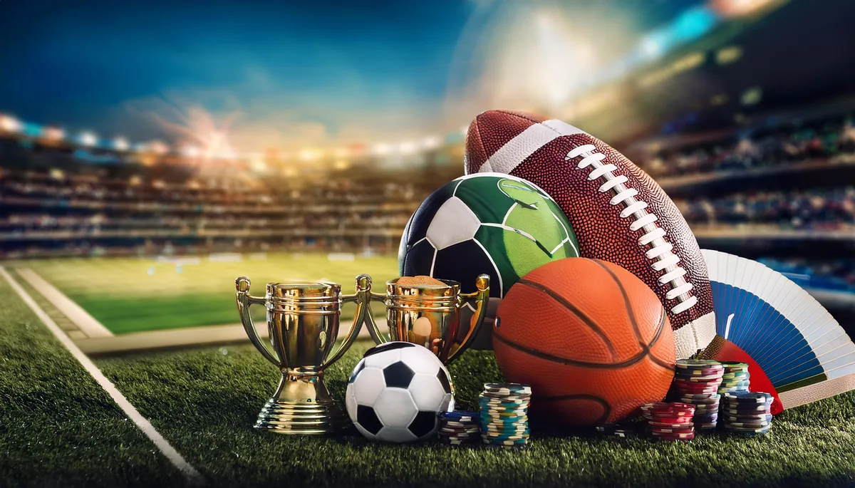 Cricket, football and tennis equipment with trophies inside a floodlit stadium